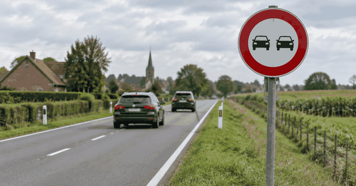 Belgisch rood-wit inhaalverbodbord langs een tweestrooksweg met auto’s die netjes achter elkaar rijden